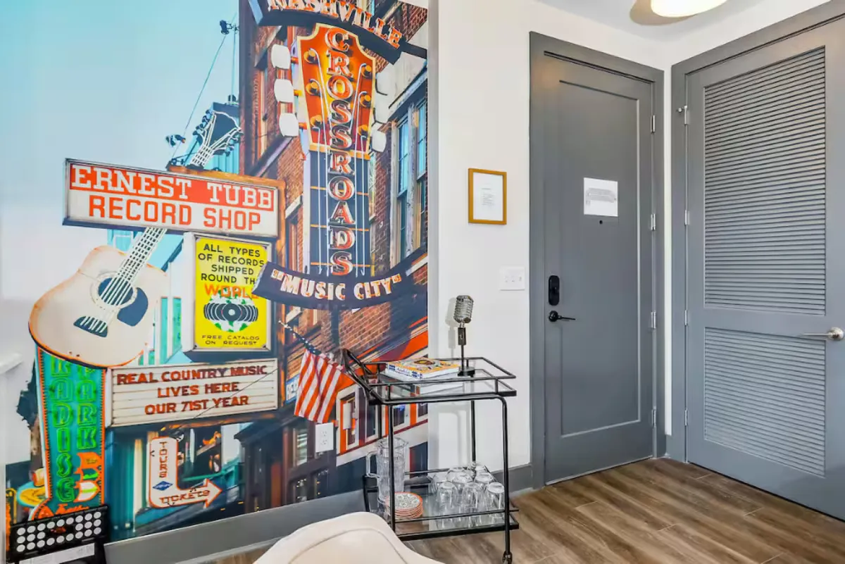 An artistic interior scene featuring a vintage record shop mural, a classic microphone, and a stylish cart with glasses. The nostalgic decor pays homage to Nashville's unmatched music culture and invites group gatherings or music appreciation moments.